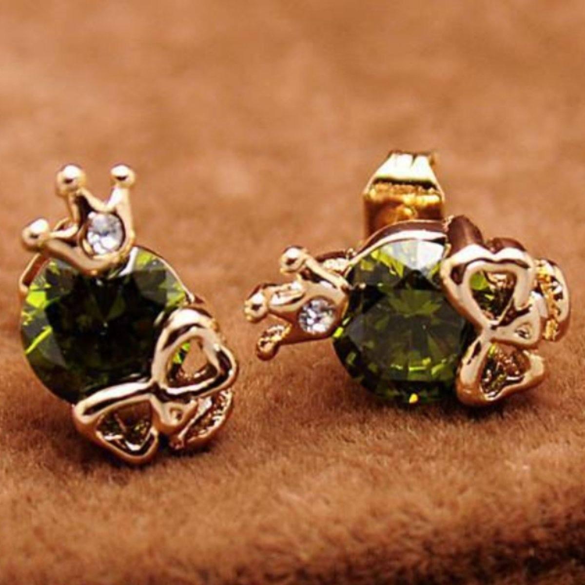 A pair of Woman's Gold Plated Skull Cubic Zircon stud earrings on a brown surface.