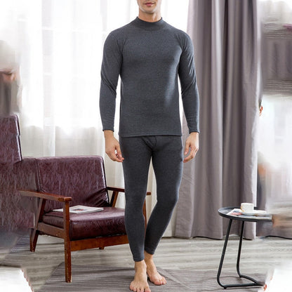 A person stands in a room, wearing Men's Soft Winter Thermal Underwear - Dark Gray. The premium long-sleeve top and matching bottoms provide warmth. A chair and small table with a cup and book are visible in the background.